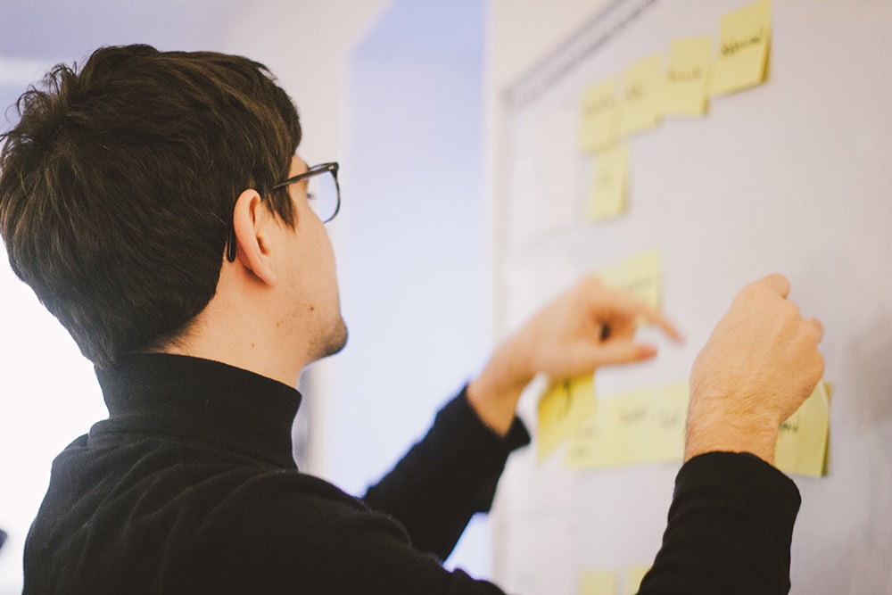 Mann an Whiteboard, sortiert Zettel