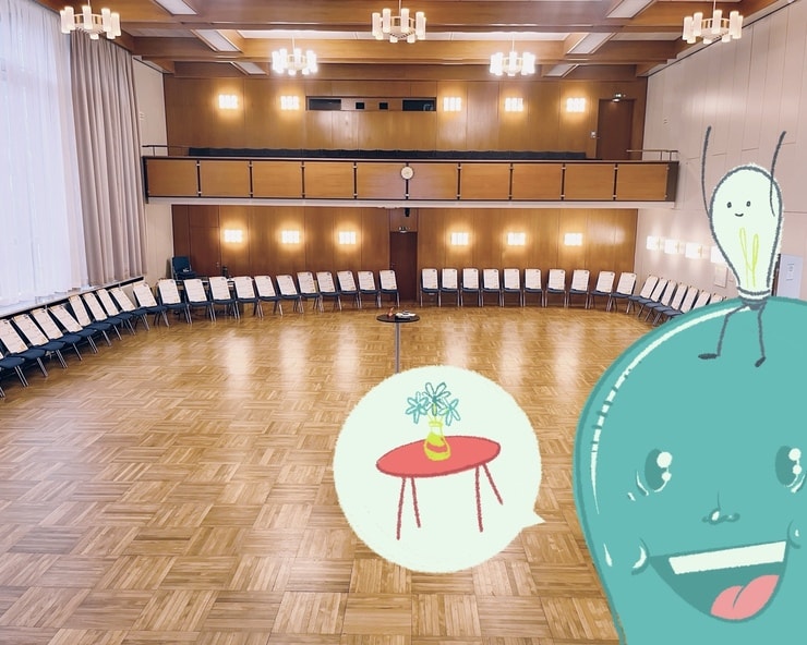 Ein Raum mit Stuhlkreis, mit einem Tisch in der Mitte. Illustration mit einer Sprechblase mit einem Tisch und einer Vase darauf.